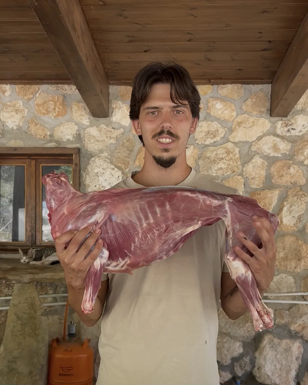 Iker sosteniendo la canal de un cabrito en la finca de Vida en Vela